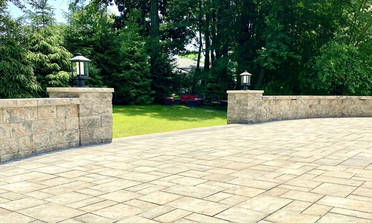 A NJ masonry job with large rectangular pavers surrouned by a waist high wall with accent lights near the entrance.