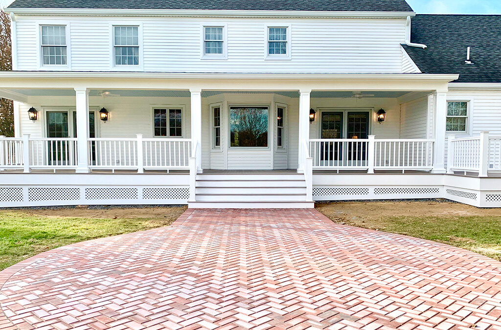 A back porch on a white house featuring paving stones leaving to large back stairs.