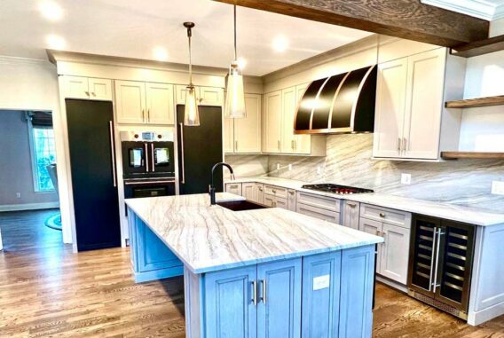 An open-concept kitchen in Watchung, NJ with new hardwood flooring, open ceiling beam, and new cabinetry with marble countertops.
