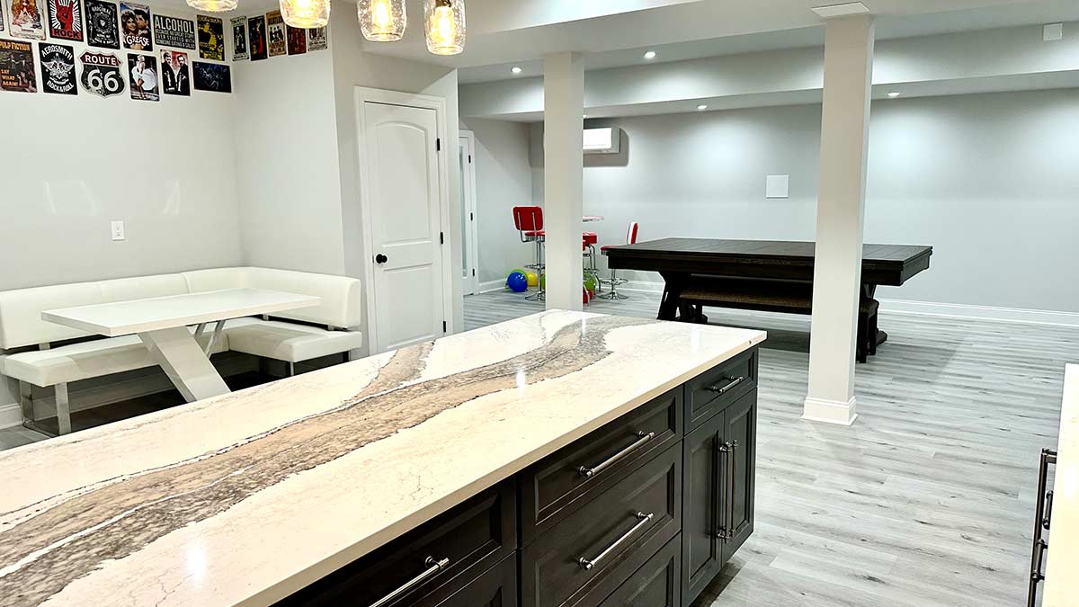 A Westfeild, NJ basement remodel with brand new flooring, drywall, with a custom-built wetbar featuring a marble top and dark cabinetry.