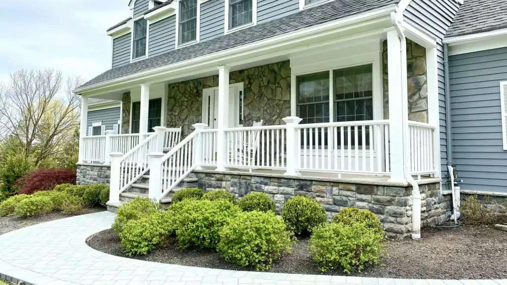 stone-walkway-leading-to-white-porch-and-blue-house