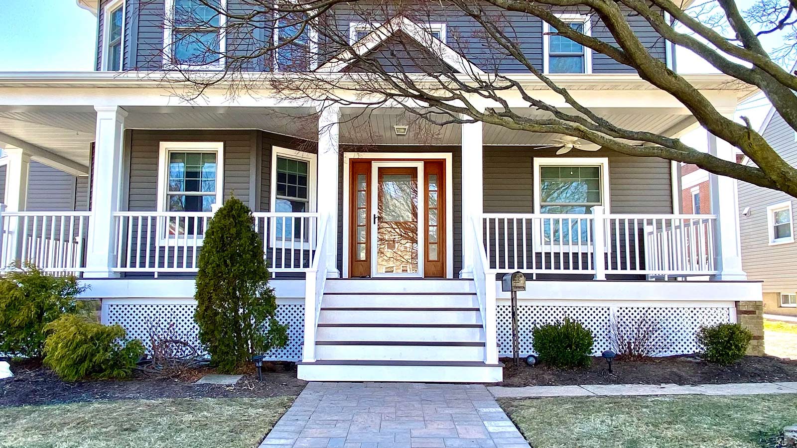 white-porch-on-blue-house-with-wood-framed-doorway-and-stone-pathway