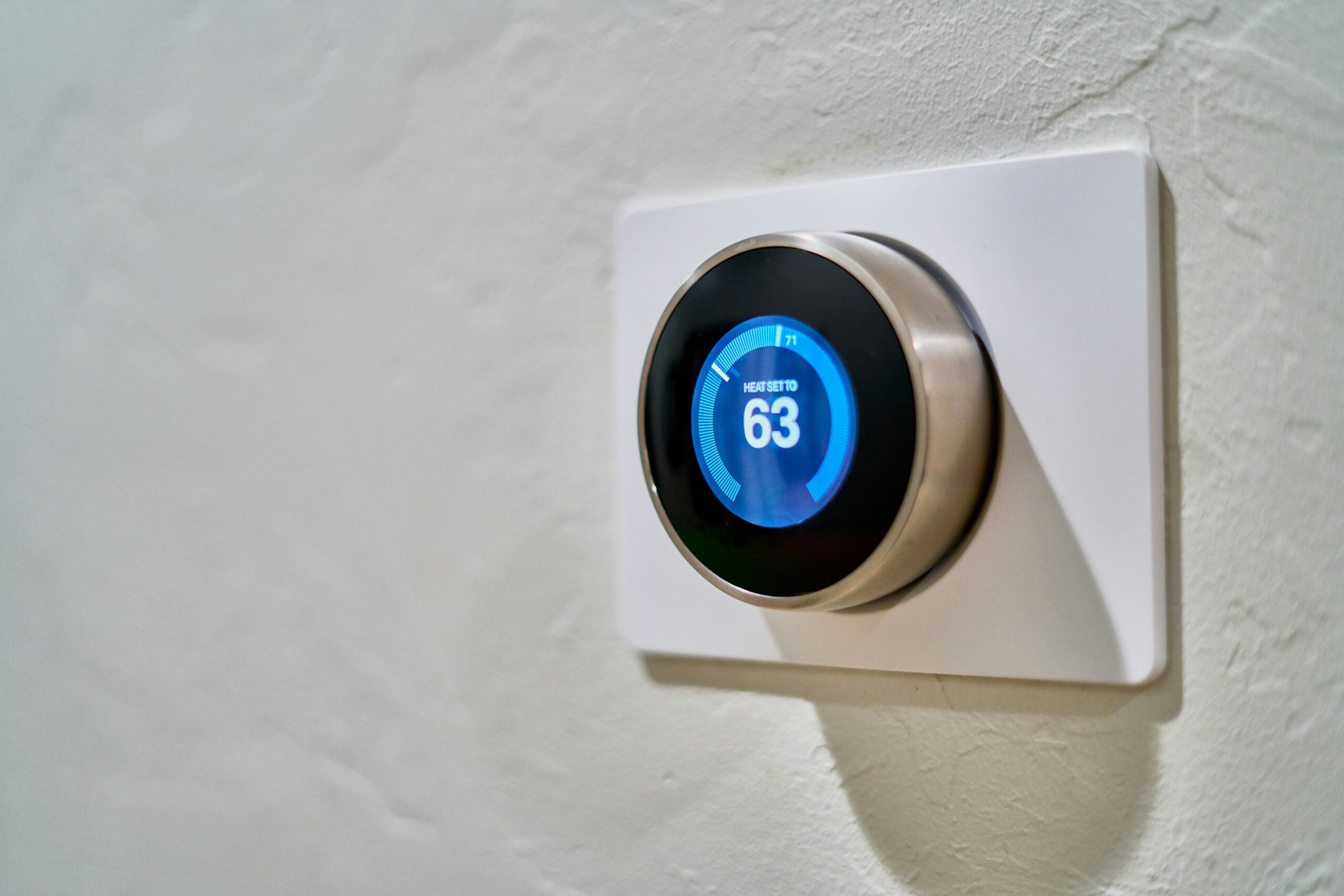 Wall-mounted smart thermostat displaying temperature settings, illustrating energy-saving smart home features and automated climate control.