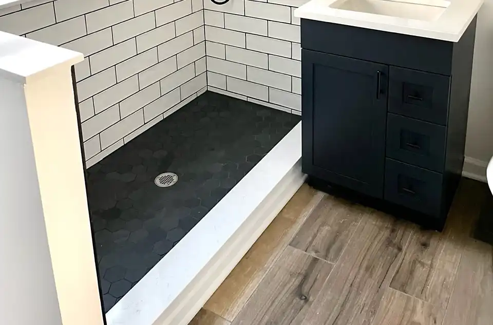 Detail of the light colored hardwood floor paired with white tile and dark cabinetry.